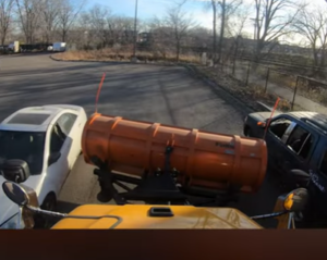 Still image from a video of snowplow operator training that uses junk cars as props.
